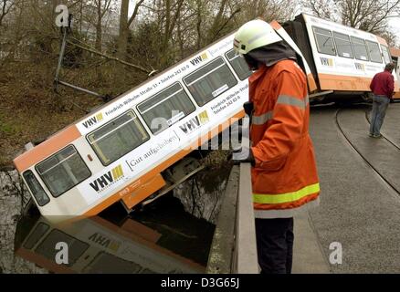 (Dpa) - un vigile del fuoco (L) appare in un tram che si blocca la testa prima attraverso un ponte con la cabina di guida nell'acqua del fiume Oker di Braunschweig, Germania, 18 novembre 2003. La fermata del tram è venuto fuori le sue vie e sono caduto attraverso la ringhiera del ponte in cui il primo carrello sbarcati testa prima nell'acqua. L'incidente è stato presumibilmente causato dalla vite da un carrello che giace sulla pista Foto Stock