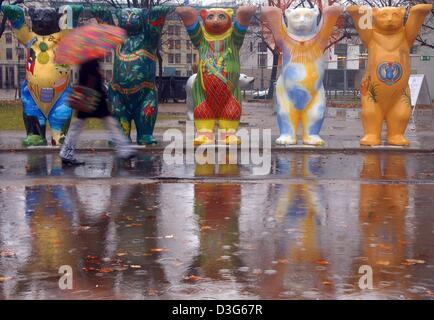 (Dpa) - Una donna con un ombrello passeggiate dopo una fila di colorati dipinti buddy bear sculture in Berlino, 17 novembre 2003. Questo autunno sarà molto umide e piovose. Foto Stock