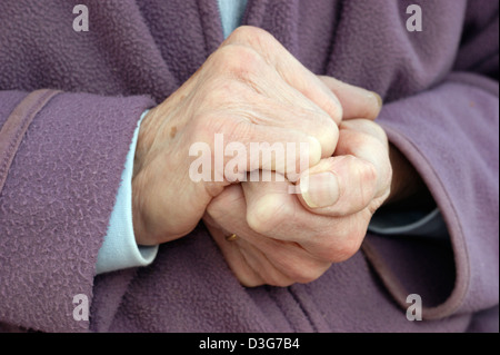 In prossimità delle mani di una donna anziana che indossa una giacca di lana e una calda sciarpa cercando di tenere in caldo in condizioni di basse temperature Foto Stock