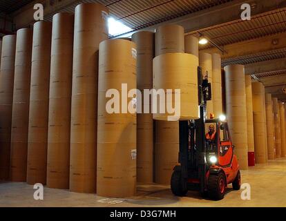 (Dpa) - una forcella di sollevamento solleva un rotolo di carta su una fila neetly ammucchiati rotoli di carta a magazzino di Rhein Papier, produttore di carta, Hurth, Germania 23 ottobre 2003. La società dei produttori di carta riciclata al 100% carta vecchia. Il produce fino a 280.000 tonnellate di carta per vari clienti nel settore dell'editoria, giornali e riviste. 'Drupa', il più grande del mondo di carta Foto Stock