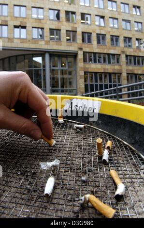 (Dpa) - Un uomo mette fuori una sigaretta in un posacenere al di fuori di un edificio per uffici a Francoforte, 16 novembre 2004. I datori di lavoro e sindacati in Germania stanno attualmente discutendo se le pause sigaretta dovrebbe essere consentito pagato durante le ore di lavoro. I datori di lavoro richiedono che il fumo negli uffici di essere totalmente vietate. Foto Stock