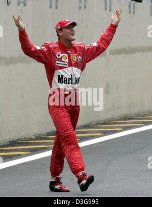 (Dpa) - Ferrari il tedesco di Formula Uno del campione del mondo in carica Michael Schumacher gesti come egli arriva in ritardo come piloti di Formula Uno rappresentano per i fotografi prima dell'inizio del brasiliano di FORMULA ONE Grand Prix sul circuito di Interlagos in Sao Paulo, Brasile, domenica 24 ottobre 2004. Foto Stock