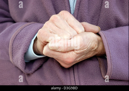 In prossimità delle mani di una donna anziana che indossa una giacca di lana e una calda sciarpa cercando di tenere in caldo in condizioni di basse temperature Foto Stock