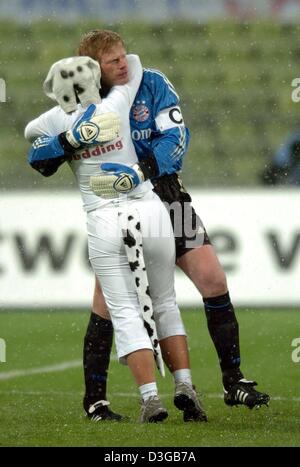 (Dpa) - Bayern Monaco di Baviera goalie Oliver KAHN (R) è abbracciato da un ventilatore che è rivestita di un costume del cane e correva sul campo durante il tedesco Cup Soccer Game tra FC Bayern Monaco e VfB Stoccarda a Monaco di Baviera, Germania, 10 novembre 2004. Il Bayern Monaco ha vinto il gioco di 3-0. Foto Stock