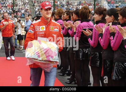 (Dpa) - Tedesco pilota di Formula Uno Michael Schumacher porta un kimono, un presente dal suo driver, come egli cammina tra due corsie di ragazze della griglia durante la sfilata conducente il il circuito di gara a Suzuka, in Giappone, 10 ottobre 2004. Sullo sfondo a sinistra il suo compagno di squadra Rubens Barrichello. Foto Stock