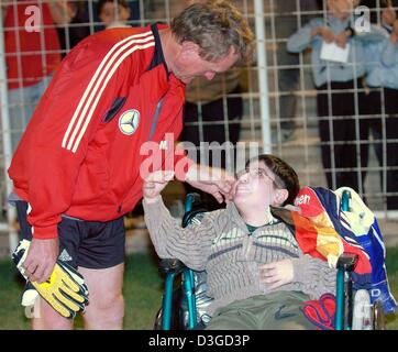 (Dpa) - Tedesco goalkeeping coach Sepp Maier saluta un bambino iraniano che è seduto in una sedia a rotelle e a un campo da calcio a Tehran, Iran, 7 ottobre 2004. Il calcio tedesco team farà incontrare Iran sulla squadra nazionale in un amichevole internazionale sabato 9 ottobre 2004. Foto Stock