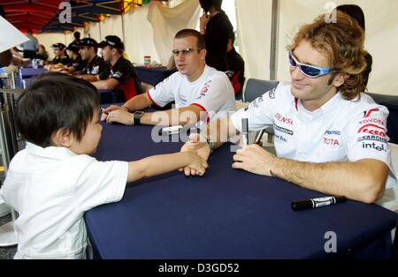 (Dpa) - Italiano pilota di formula uno Jarno Trulli (Toyota) scuote le mani con un po' di giapponese ventola come i driver firmare autografi sul circuito di gara a Suzuka, in Giappone, 7 ottobre 2004. Il giapponese di FORMULA ONE Grand Prix che sarà in corso la domenica, 10 ottobre 2004, è Trulli della prima gara per il suo nuovo team. Foto Stock