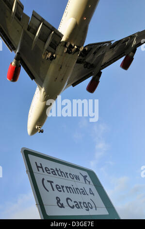 L'aereo di linea Boeing 747 atterra all'aeroporto di Londra Heathrow, come illustrato dal cartello stradale. Jumbo Jet Foto Stock