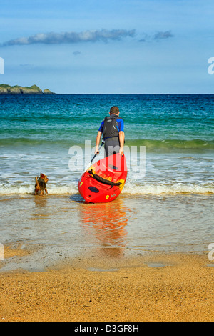 Uomo maturo con una canoa e cane, Harlyn Bay, Cornwall, Inghilterra Foto Stock