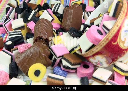 Un sacco di liquirizia dolci e panini al cioccolato fuoriuscita da una ciotola capovolta Foto Stock