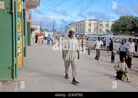 Un uomo cammina davanti a un insieme di aprire negozi su strade trafficate di Mogadiscio, Somalia. Foto Stock