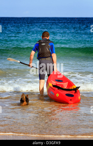 Uomo maturo con una canoa e cane, Harlyn Bay, Cornwall, Inghilterra Foto Stock