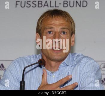 (Dpa) - Juergen Klinsmann, allenatore della nazionale tedesca di calcio, e parla come egli siede sotto il logo del calcio tedesco federation (DFB) nel corso di una conferenza stampa a Berlino, Germania, 2 settembre 2004. La Germania si incontreranno il Brasile in una partita amichevole a Stadio Olimpico di Berlino mercoledì 8 settembre 2004. Foto Stock