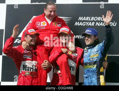 (Dpa) - Tedesco pilota di Formula Uno Michael Schumacher (2a da R) della Ferrari cheers insieme con il suo compagno di squadra brasiliano Rubens Barrichello (L), la Ferrari del team leader Jean Todt (2a da L) e spagnolo pilota di Formula Uno della Renault Fernando Alonso dopo aver vinto l'Ungherese FORMULA ONE Grand Prix sul circuito di Hungaroring racing circuito di Budapest, Ungheria il 15 agosto 2004. Schumacher mi Foto Stock