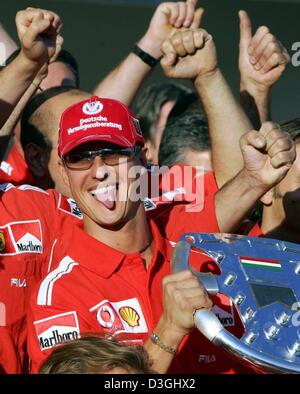 (Dpa) - Tedesco pilota di Formula Uno Michael Schumacher (C) cheers e celebra tra i membri del team Ferrari dopo aver vinto l'Ungherese FORMULA ONE Grand Prix sul circuito di Hungaroring racing circuito di Budapest, Ungheria il 15 agosto 2004. La Scuderia Ferrari ha vinto il titolo di campione del mondo di Formula Uno di ingegneria. Schumacher è ora in grado di fissare il suo settimo mondiale champio Foto Stock