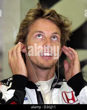 (Dpa) - British pilota di Formula Uno Jenson Button (BAR Honda) ha inserito le sue orecchie con gli auricolari sul circuito di Hungaroring racing circuito di Budapest, Ungheria, 13 agosto 2004. L'Ungherese FORMULA ONE Grand Prix sarà in corso la domenica, 15 agosto 2004. Foto Stock