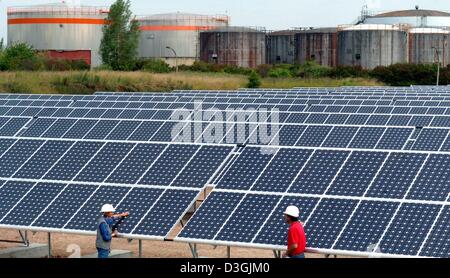 (Dpa) - due dipendenti a stare di fronte di righe di grandi pannelli solari a uno dei più grandi in tutto il mondo impianti fotovoltaici in Krumpa, Germania, 30 giugno 2004. La centrale solare è stato costruito nei locali di un ex raffineria di petrolio e copre un aera di circa 160.000 metri quadrati con un massimo di 25, 000 mono e poli cristallino di moduli solari in appoggio su 777 telai metallici. La potenza pl Foto Stock