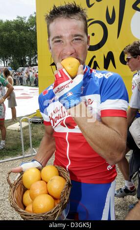 (Dpa) - ciclista francese Thomas Voeckler del team Brioches La Boulangere morde un arancione dopo aver ricevuto il "Prix d'arancia', prima della ventesima fase del 2004 Tour de France corsa di ciclismo in Montereau, Francia, 25 luglio 2004. Il Prix d'arancio è aggiudicato da fotografi che copre il Tour da motorcyles al più fotogenica e più belle ciclista del Tour. L'ex quasi u Foto Stock