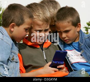 (Dpa) - Otto anni di old boys Lars, Philipp, Felix e Niels stringersi intorno a un Game Boy video portatile in gioco Neukirchen-Vluyn, Germania, 21 giugno 2004. Portable video games sono molto popolari fra i bambini. Foto Stock