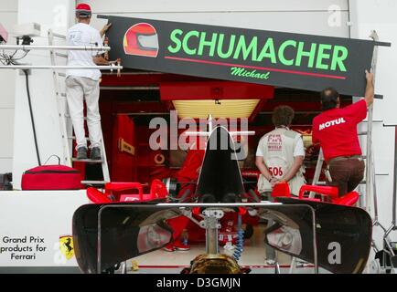 I lavoratori si applica la targhetta del nome del tedesco pilota di Formula Uno Michael Schumacher alla Ferrari pit sulla gara di Magny Cours corso in Francia, giovedì 1 luglio 2004. Il Gran Premio di Francia sarà in corso domenica 4 luglio 2004. Foto Stock