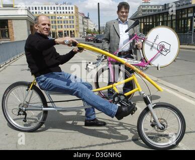 (Dpa) - Mentre ex Olimpico Tedesco di Coppa del mondo e campione di ciclismo Werner Otto (L) si siede sul mondo del apparentemente più comode biciclette, ex Jan Ullrich coach Peter Becker mostra la bicicletta usata da Ullrich durante il 2001 Tour de France a Berlino, Germania, 16 giugno 2004. La nuova moto sarà visualizzata insieme con la più grande del mondo di bicicletta prossimo sabato. Foto Stock