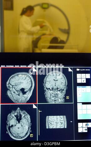 (Dpa) - Un dipendente (fondo) è preparato per un MRI scan al gruppo di ricerca Magnetico Resonance (MR) Ricerca in Neurologia e psichiatria" presso la clinica Universitaria di Goettingen, Germania, 20 gennaio 2004. In primo piano la sezione immagini di un cervello sono visibili su uno schermo. Il romanzo MRI scan tecnica aiuta a trovare nuovi approfondimenti sulle malattie neurologiche e psichiatriche Foto Stock