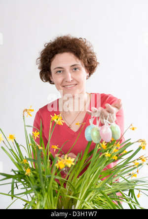 Giovane donna ricci trattiene le uova di pasqua e andando a nascondere le uova in giallo narciso Foto Stock