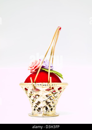 Una miniatura in vimini metallico decorata da rose su un velluto rosso isolato su sfondo bianco Foto Stock