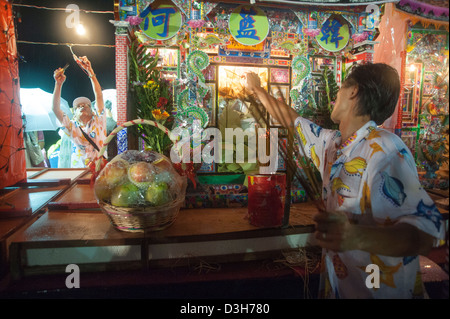 Gli uomini di pregare per le case costruite per i loro antenati durante il cinese Ghost 'festival' in Keelung, Taiwan Foto Stock