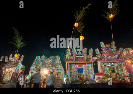 Gli uomini di pregare per le case costruite per i loro antenati durante il cinese Ghost 'festival' in Keelung, Taiwan Foto Stock