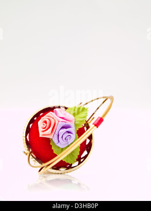 Una miniatura in vimini metalic decorate da rose su un velluto rosso isolato su sfondo bianco Foto Stock