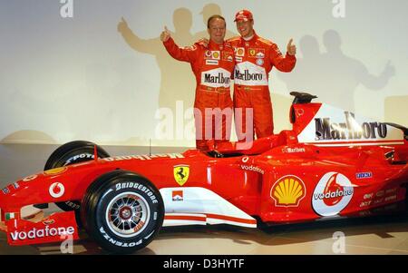 (Dpa) - Tedesco pilota di Formula Uno Michael Schumacher e il pilota brasiliano Rubens Barrichello (L) gesto il pollice in alto segno dopo la nuova Ferrari auto di Formula Uno per la stagione 2004 è stata svelata a Maranello, Italia, 26 gennaio 2004. La stagione di Formula Uno prende il via il 7 marzo in Australia. Foto Stock