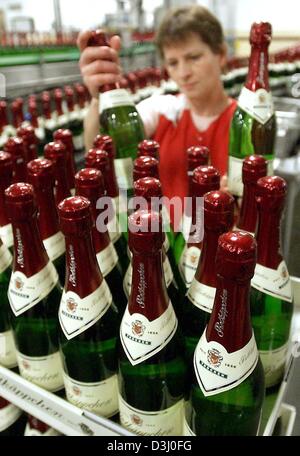 (Dpa) - Un dipendente controlla le bottiglie di Rotkaeppchen Sekt (Rotkaeppchen vino spumante) su una linea di imbottigliamento presso il vino spumante produttore Rotkaeppchen-Mumm in Freyburg, Germania orientale, 19 dicembre 2003. Circa trenta per cento della quantità annuale di vino spumante è venduto in novembre e dicembre. Foto Stock
