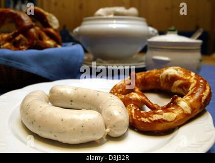 Due tradizionali bavaresi salsicce di carne di vitello e un pretzel giacciono su di un piatto pronto per essere mangiato in un ristorante di Monaco di Baviera, Germania, 20 gennaio 2004. La città di Monaco di Baviera ha preso i lati a nome della città macellai e i padroni di casa riguardante un argomento che solo quelle bavaresi salsicce di carne di vitello, che sono prodotti di Monaco possono essere chiamati bavarese salsicce di vitello. Foto Stock