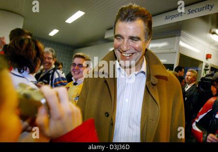 (Dpa) - Heiner Marca (L), allenatore della nazionale tedesco di squadra di pallamano, sorrisi nelle telecamere al suo arrivo all aeroporto di Francoforte sul Meno, Germania, il 2 febbraio 2004. Il tedesco della squadra di pallamano ha vinto il campionato europeo il 1 febbraio 2004 in una finale contro la Slovenia. Brand ha dovuto riempire in su le condizioni di una scommessa e rasato fuori il suo marchio di baffi. Foto Stock