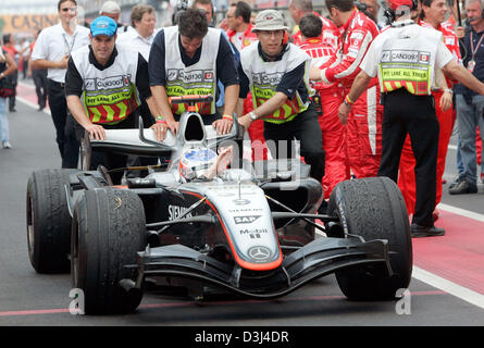 (Dpa) - Finlandese pilota di Formula Uno Kimi Raikkonen (C) della McLaren Mercedes arriva al pit lane dopo egli vincere in Formula One Grand Prix del Canada al corso canadese Gilles Villeneuve a Montreal, Canada, Domenica, 12 giugno 2005. Raikkonen ha vinto davanti alla Ferrari il pilota tedesco Michael Schumacher e il pilota brasiliano Rubens Barrichello. Foto Stock