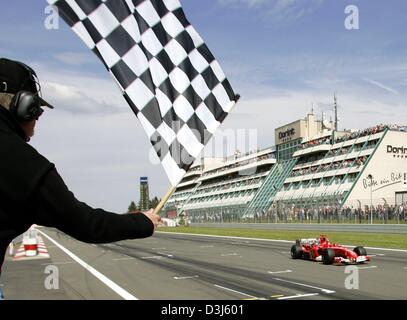 (Dpa) - tedesco di Formula Uno del campione del mondo in carica Michael Schumacher (Ferrari) comanda il passato sotto la bandiera a scacchi al traguardo del Gran Premio Europeo al Nuerburgring race track in Germania, 30 maggio 2004. Foto Stock