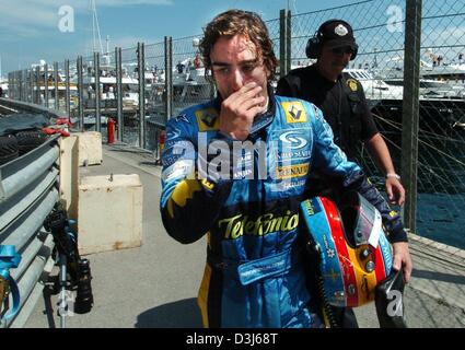 (Dpa) - Spagnolo pilota di Formula Uno della Renault Fernando Alonso passeggiate deluso con il suo casco sotto il suo braccio passato la città di cours dopo un crash durante il Grand Prix di Formula 1 di Monaco, 23 maggio 2004. Foto Stock