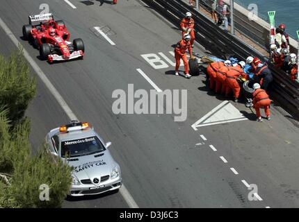 (Dpa) - La safety car e tedesco pilota di Formula Uno Michael Schumacher (L) guidare passato pilota spagnolo Fernando Alonso (R, Renault) che si è schiantato contro una ringhiera durante il Gran Premio di Formula 1 di Monaco, 23 maggio 2004. Foto Stock