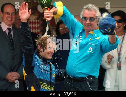 (Dpa) - capo del team Renault Flavio Briatore (R), versa una bottiglia di champagne sulla testa di italiano pilota di formula uno Jarno Trulli (C) della Renault dopo il Gran Premio di Formula 1 di Monaco, 23 maggio 2004, mentre il Principe Alberto di Monaco (L, indietro) e la Principessa Caroline (R, indietro) a guardare. Trulli, che hanno iniziato la pole-position, ha vinto il Grand Prix di Monaco e ha celebrato il primo Foto Stock