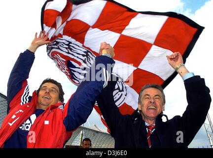 (Dpa) - del Bayern Monaco soccer allenatore Ottmar Hitzfeld (R) e il suo co-allenatore Michael Henke cheers e jubilate di fronte il club di bandiera dopo la Bundesliga soccer game contrapposta FC Bayern Monaco e SC Freiburg a Monaco di Baviera, Germania, il 22 maggio 2004. Hitzfeld sta per lasciare il Bayern Monaco dopo sei anni come il club di calcio del pullman. Foto Stock