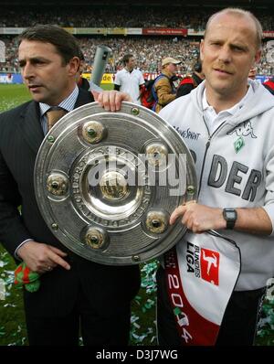 (Dpa) - Brema allenatore di calcio Thomas Schaaf e Brema del gestore Klaus Allofs sorriso come essi pongono con la Bundesliga tedesca trofeo nelle loro mani dopo la Bundesliga soccer game contrapposta SV Werder Brema e Bayer 04 Leverkusen in Bremen, Germania, 15 maggio 2004. Brema aveva già fissato la Bundesliga 2003/2004 titolo di campione nel gioco del calcio contro il Bayern Monaco di Baviera due giorni Foto Stock