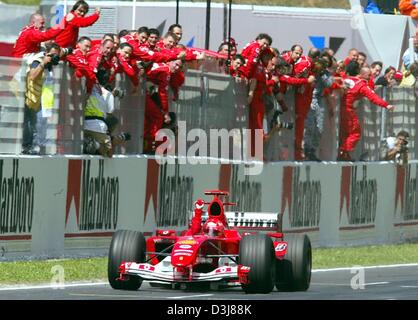 (Dpa) - Tedesco pilota di Formula uno e il campione del mondo Michael Schumacher della Ferrari si solleva il pugno dalla sua vettura da corsa come egli passa vicino l'intero equipaggio Ferrari, dopo aver vinto il Gran Premio di Spagna sul circuito di Formula Uno a Barcellona, Spagna, 9 maggio 2004. Foto Stock