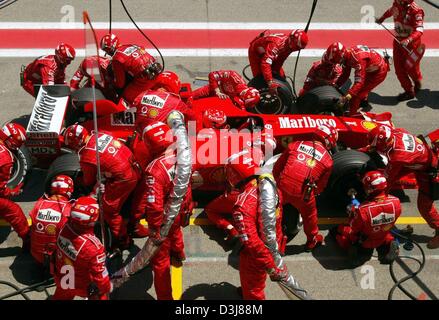 (Dpa) - Tedesco pilota di Formula uno e il campione del mondo Michael Schumacher si siede nella sua vettura da corsa mentre i tecnici Ferrari continua a lavorare sulla vettura durante un pit stop durante il Gran Premio di Spagna sul circuito di Formula Uno a Barcellona, Spagna, 9 maggio 2004. Foto Stock