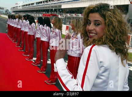 (Dpa) - una riga della griglia linea ragazze fino a fianco di un tappeto rosso mentre un altro sorrisi e le onde la sua mano prima dell inizio del Gran Premio di Spagna sul circuito di Formula Uno a Barcellona, Spagna, 9 maggio 2004. Foto Stock