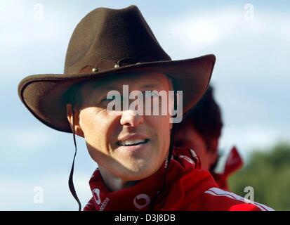 (Dpa) - Tedesco pilota di Formula uno e il campione del mondo Michael Schumacher della Ferrari indossa un cappello e sorrisi prima di cavalcare un toro meccanico vicino al circuito di formula uno di Barcellona, in Spagna, il 6 maggio 2004. Il gran premio di Spagna si terrà questo fine settimana del 8 maggio e del 9 maggio 2004. Foto Stock