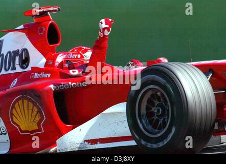 (Dpa) - Tedesco pilota di Formula uno e il campione del mondo Michael Schumacher (Ferrari) di gesti e di acclamazioni come egli unità nella sua auto racing dopo aver vinto il Gran Premio di San Marino di Imola, Italia, 25 aprile 2004. Foto Stock