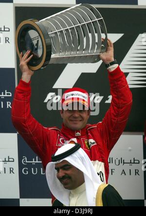 (Dpa) - Brasiliano pilota di Formula 1 Rubens Barrichello (Ferrari) cheers e mantiene alto il suo trofeo dopo aver vinto il secondo posto nella prima mai Bahrain FORMULA ONE Grand Prix in Manama, Bahrein, 4 aprile 2004. Foto Stock