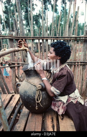 Donna etiope che riempie il suo vaso d'acqua in un rubinetto d'acqua della comunità alla periferia di Addis Abeba, Etiopia Foto Stock