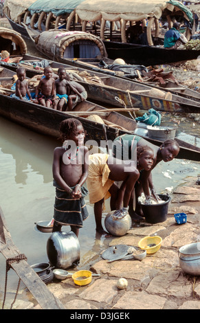 Figli della tribù Bozo, barche semi-nomadi che vivono sul fiume Niger, lavatrici pentole e padelle nel fiume. Mopti, Mali. Africa occidentale Foto Stock